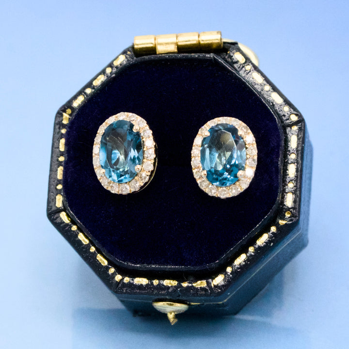 Oval London Blue Topaz Stud Earrings with Diamond Halo in Yellow Gold