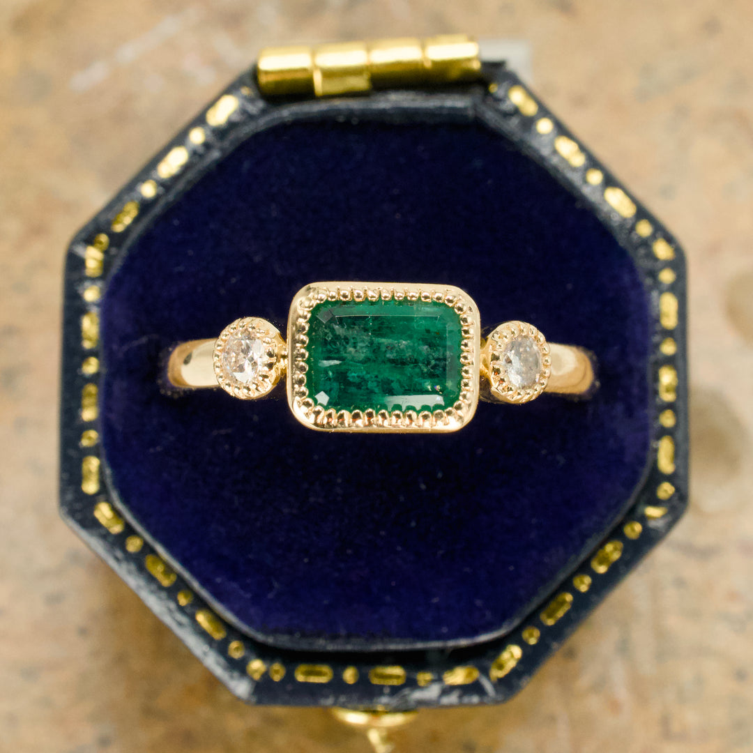 East-West Bezel Set Emerald Ring with Round Accent Diamonds in Gold