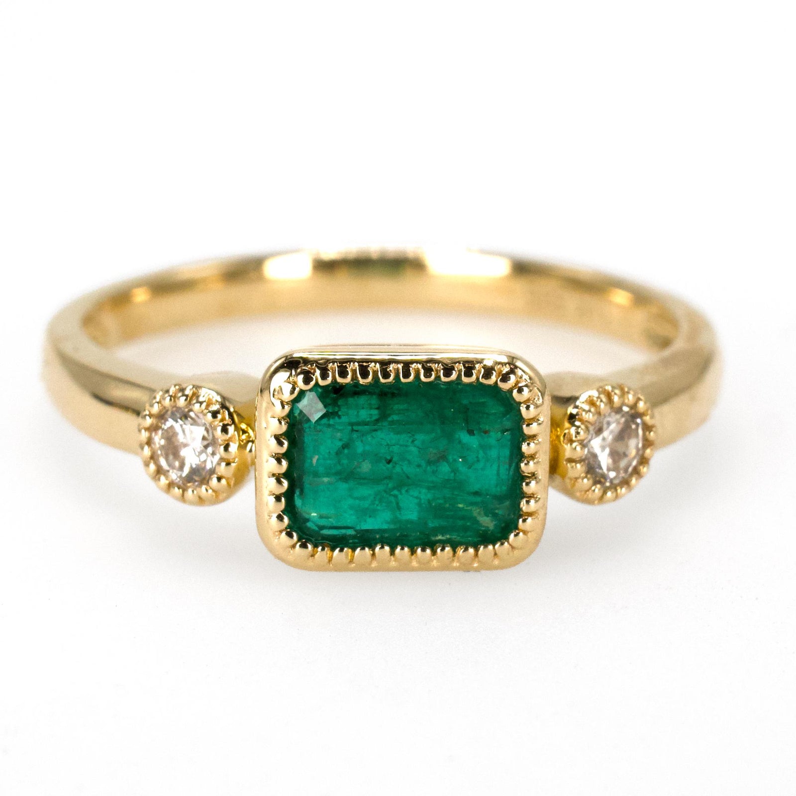 East-West Bezel Set Emerald Ring with Round Accent Diamonds in Gold