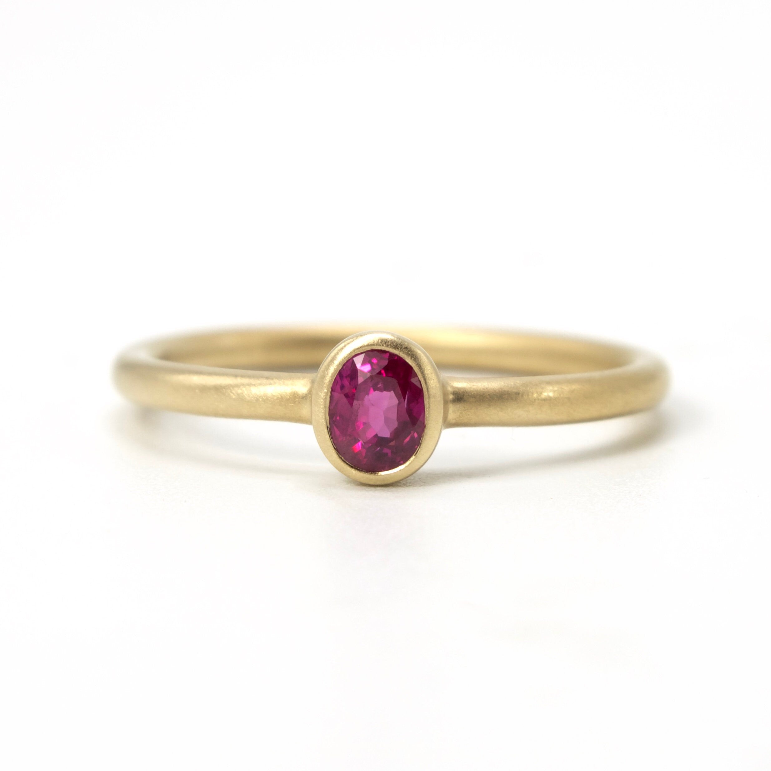 Bezel Set Oval Cut Ruby Solitaire in Brushed Gold Mounting